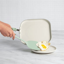 Square griddle pan with mint spatula lifting an egg from the nonstick surface.