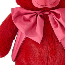 Red bear plush close-up: pink satin bow and ribbon drape