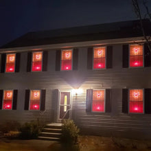 Lighted heart window silhouettes on a house exterior, glowing red through windows