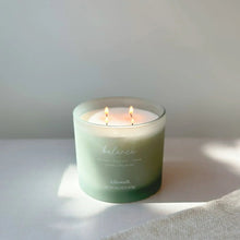 Balance spa jar candle in pale blue wax, small flames visible above the jar