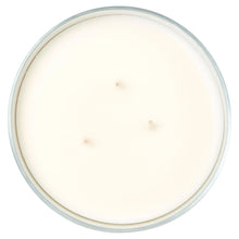 Round scented candle in clear glass jar with smooth white wax surface