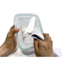 Glass food storage container with blue lid frame as a marker writes on the label area.