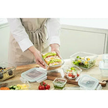 Glass food storage containers set with lids; sandwich placed into a clear container.