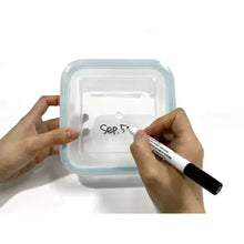 Glass food storage container front with handwritten date label in black marker.