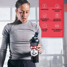 Muscle Milk protein shaker bottle held by woman in a gray long-sleeve top