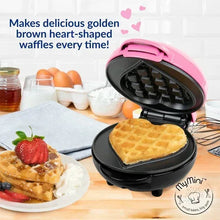 Pink mini heart waffle maker with open lid and golden waffle cooking