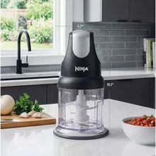 Black Ninja food chopper with clear processing cup and blade unit on countertop