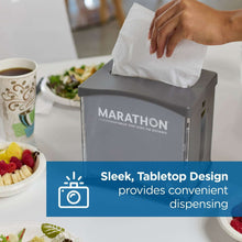 Gray countertop napkin dispenser with open lid as napkins are being inserted