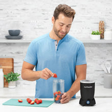 Black countertop blender with filled blending jar on prep board.