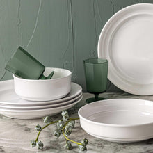 White glossy rimmed porcelain bowls and plates with green accent cups