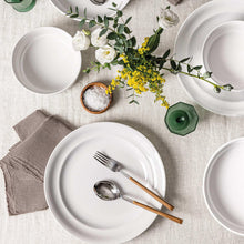 White glossy rimmed porcelain plates and bowls with forks and spoon