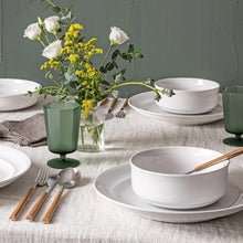 White glossy rimmed porcelain bowls and plates with gold-toned utensils