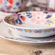 Close-up of floral dinner bowl rim, white ceramic with blue and red wildflower pattern