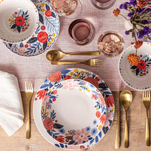 Floral dinner bowl on table with gold-toned utensils, white bowl with rose and blue border