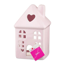 Pink ceramic house decoration with heart roof and hanging gift tag in doorway