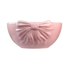 Pink ceramic serving bowl with raised bow detail on the front