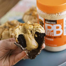 Peanut butter powder scoop with creamy spread held over a cake slice