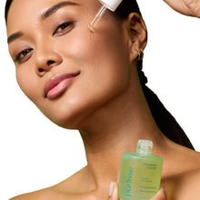 purlisse facial oil bottle held to a woman’s skin with dropper