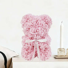 Light pink artificial rose teddy bear with white ribbon bow, sitting pose
