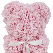 Light pink artificial rose teddy bear with white ribbon band, close-up
