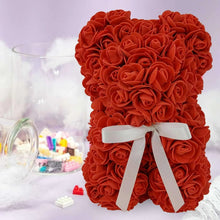 Red artificial rose bear with white ribbon bow, on decorative winter scene