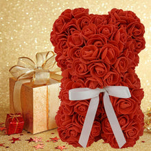 Red artificial rose bear with white ribbon bow and small gift boxes nearby