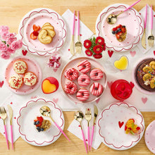Valentine party table with pink plastic drinkware cups and heart shapes