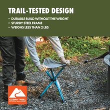 Collapsible camping stool with blue steel frame and gray fabric seat, on outdoor gravel