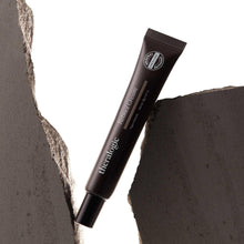 Retinol cream tube with cap, brown tube placed between textured stone edges