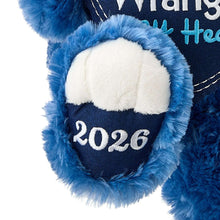 Blue teddy bear plush close-up of navy pocket with “2026”