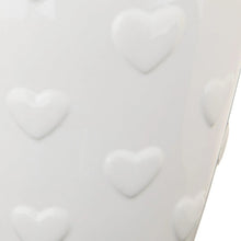 White ceramic vase close-up showing raised heart shapes