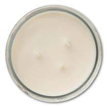 Three-wick vanilla glass jar candle with pale cream wax surface and clear rim
