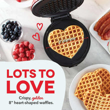 Open heart waffle maker with golden heart-shaped waffle on plate