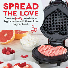 Heart waffle maker with open lid and pink heart waffle on plate